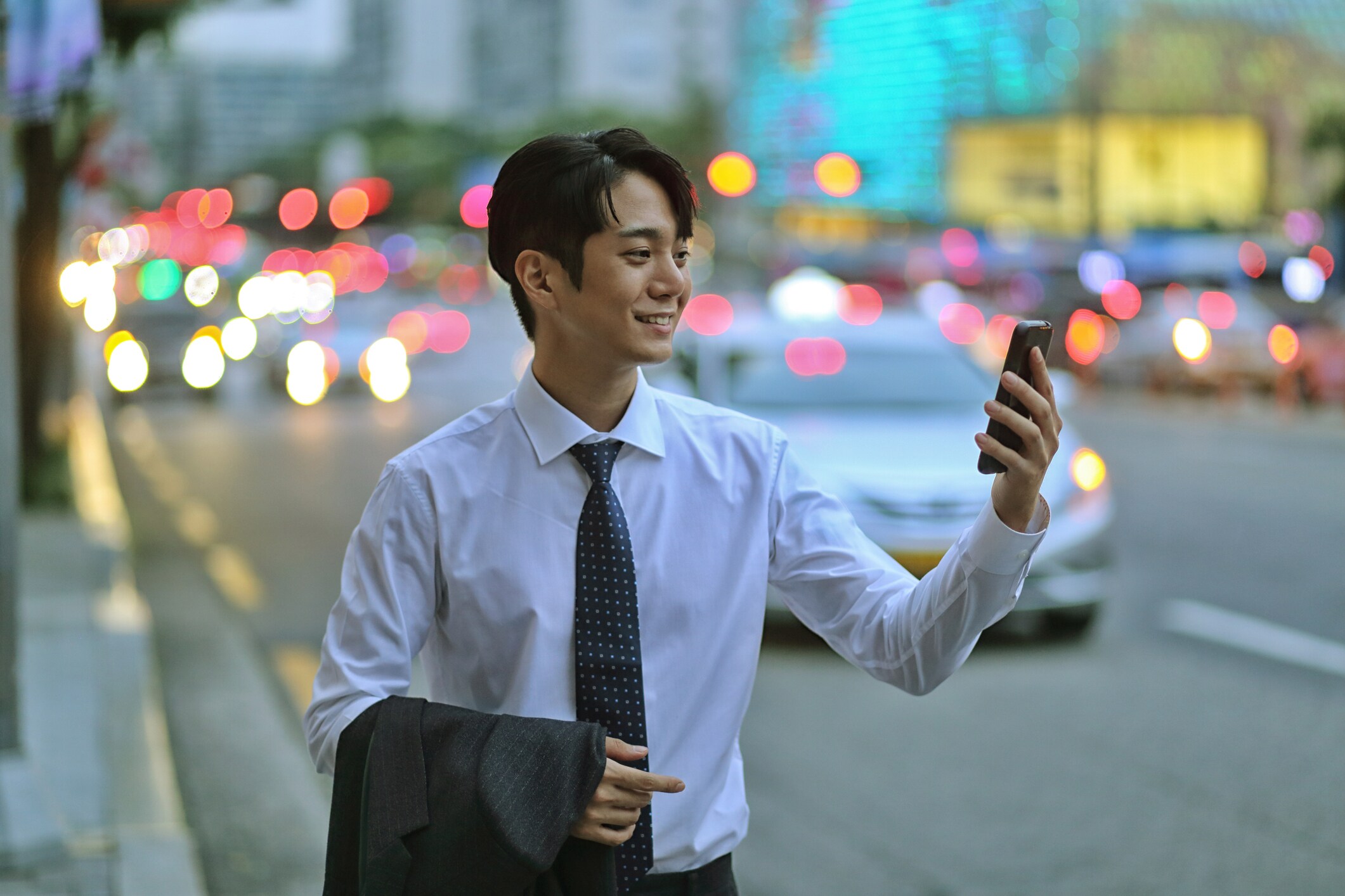 A business man walking outside, on a city street looking at his mobile phone. 