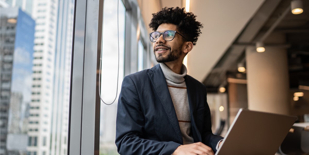 man with laptop looking out window