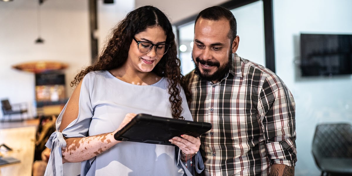 woman and man standing in office looking at tablet