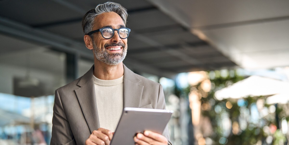 man with grey hair and glasses holding tablet