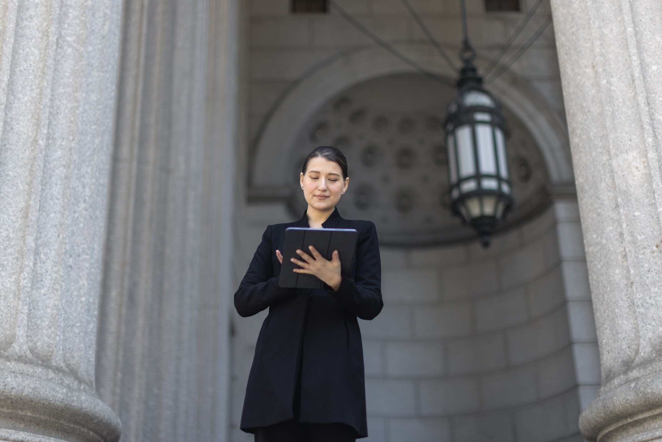 Woman standing in front of a government building looking at a tablet