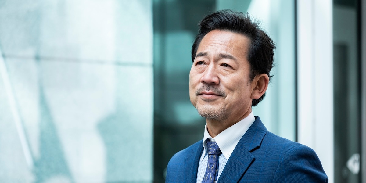 man in suit looking upward with a slight smile