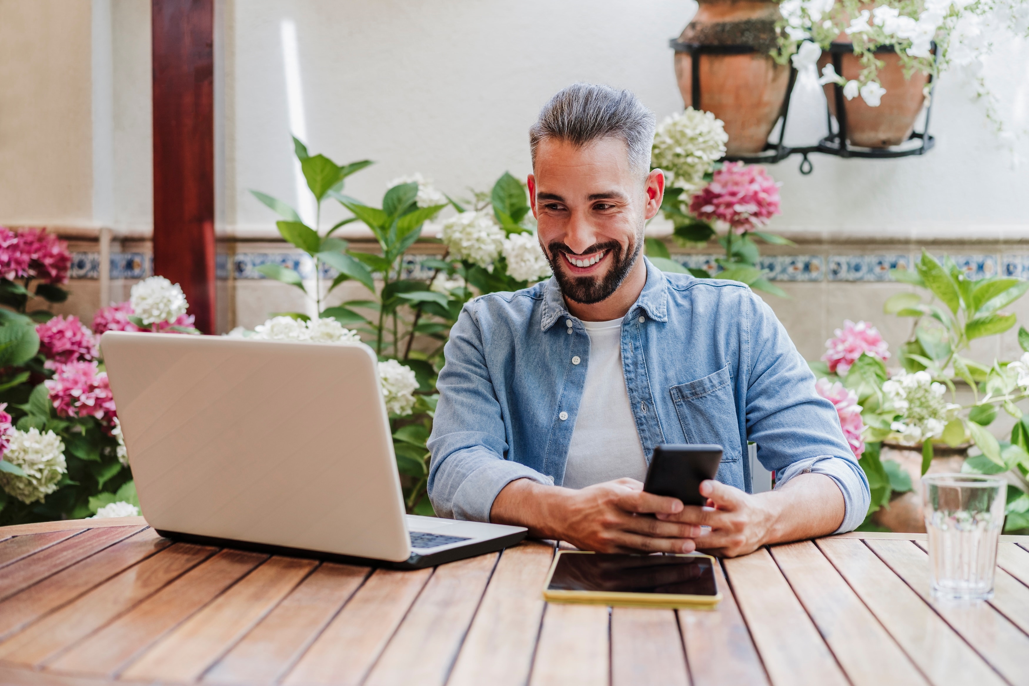 Man on his computer with his phone outside