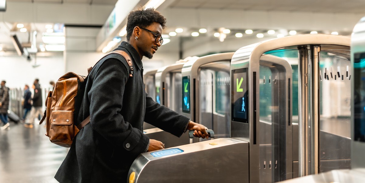 a business traveler rolls his suitcase through a turnstile gate
