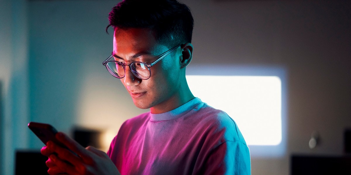 young man with glasses looking at phone