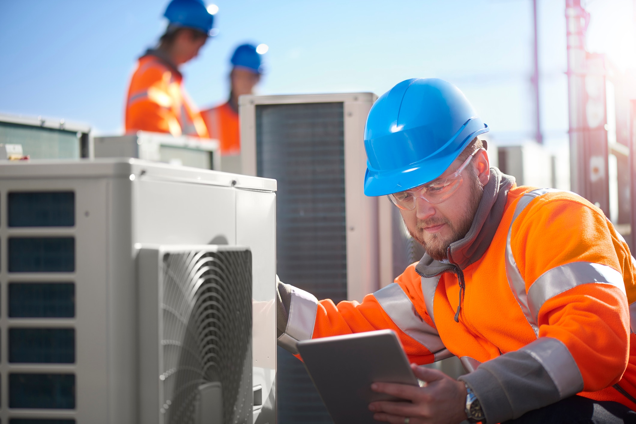 Utilities worker checking a unit looking at a tablet