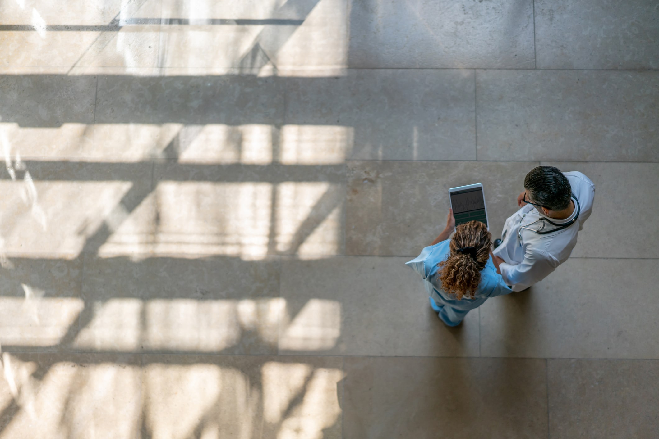 Aerial view of two healthcare professionals looking at a tablet