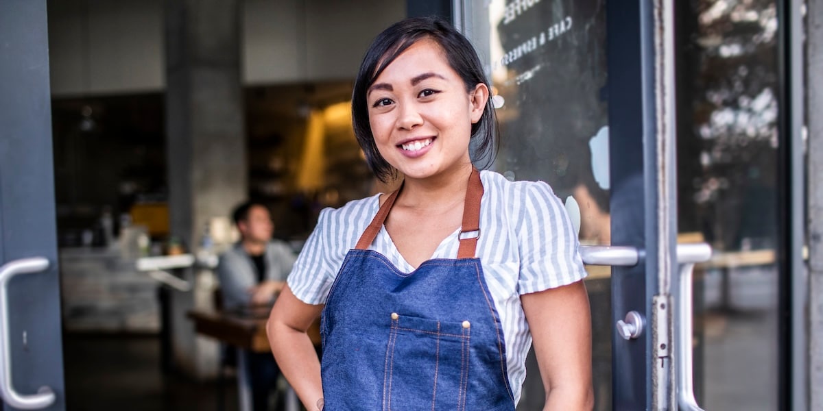 restaurant worker leaning against door smiling
