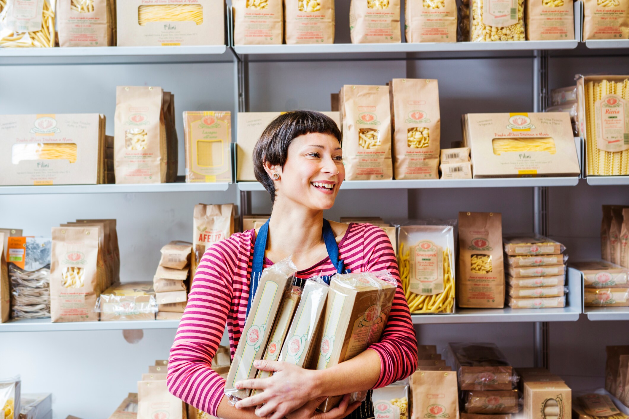 Woman in a store smiling selling packaged pasta