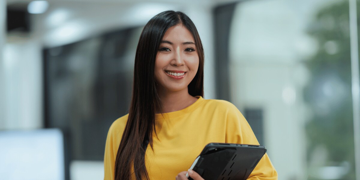 Woman smiling looking at the camera with a closed laptop in her arms