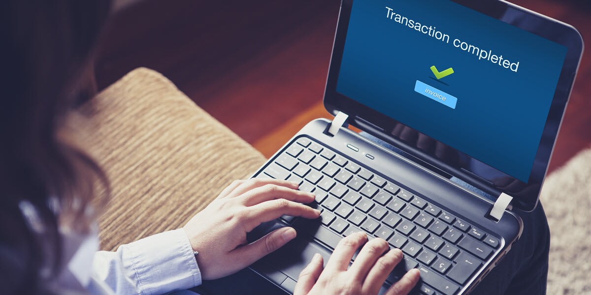 Hands on keyboard. Computer screen reads "transaction completed"
