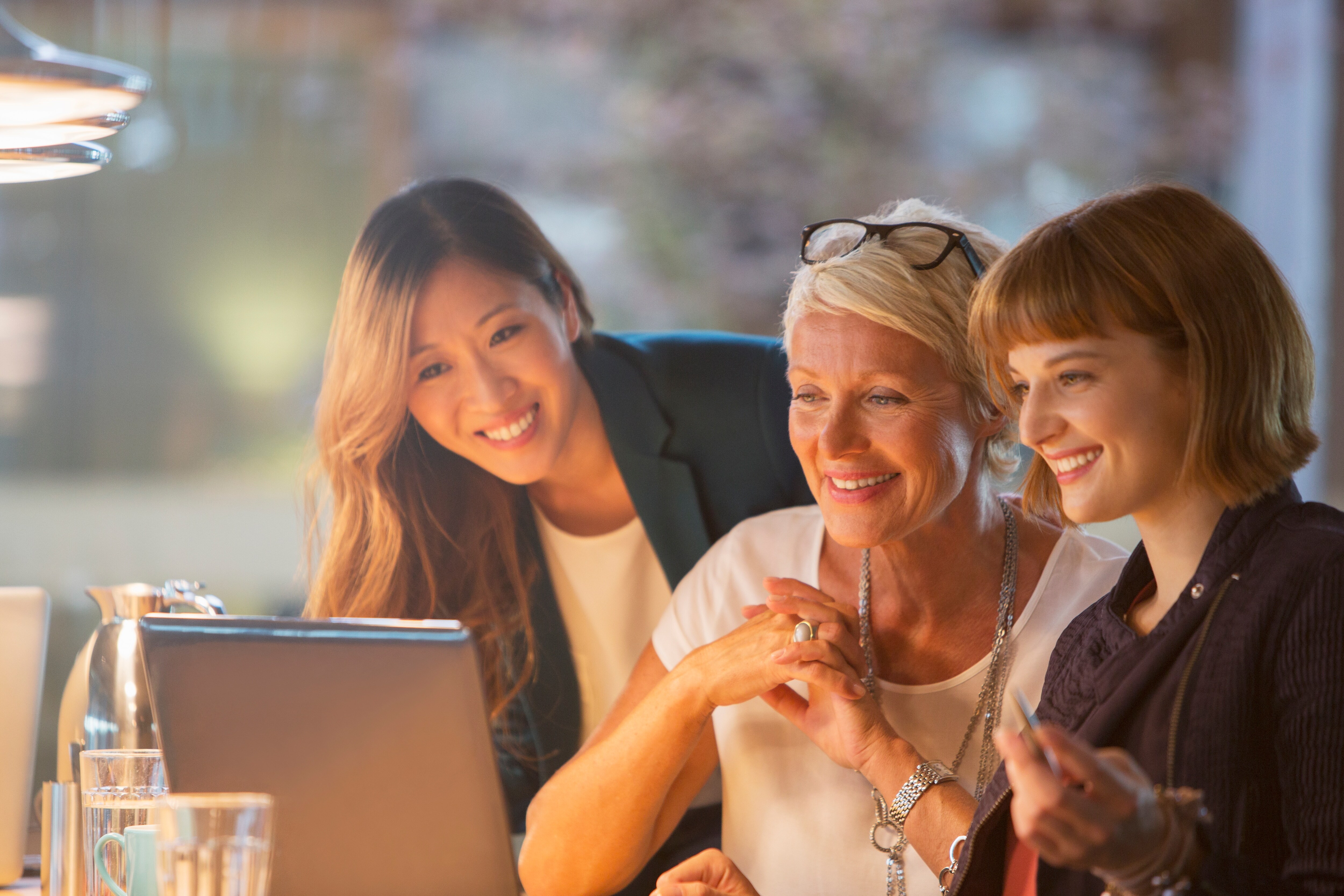 3 women are talking and looking at the screen