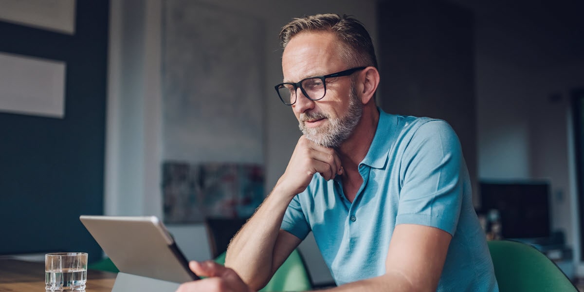 man with glasses looking at tablet 