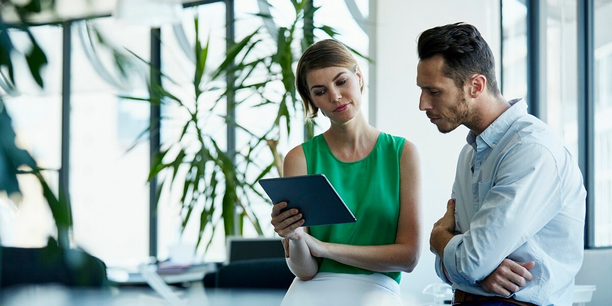 Two business people reviewing information on a tablet in an office setting