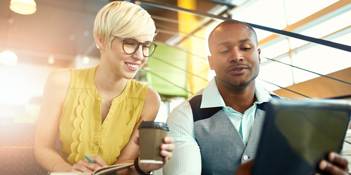 Two office workers looking over a laptop computer.