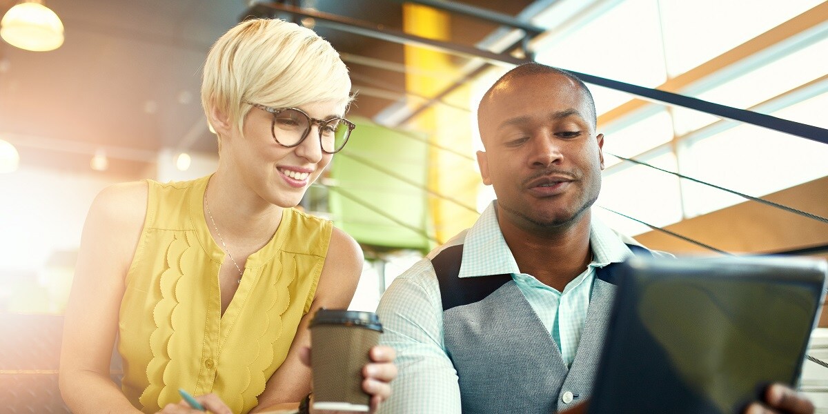 Two office workers looking over a laptop computer.