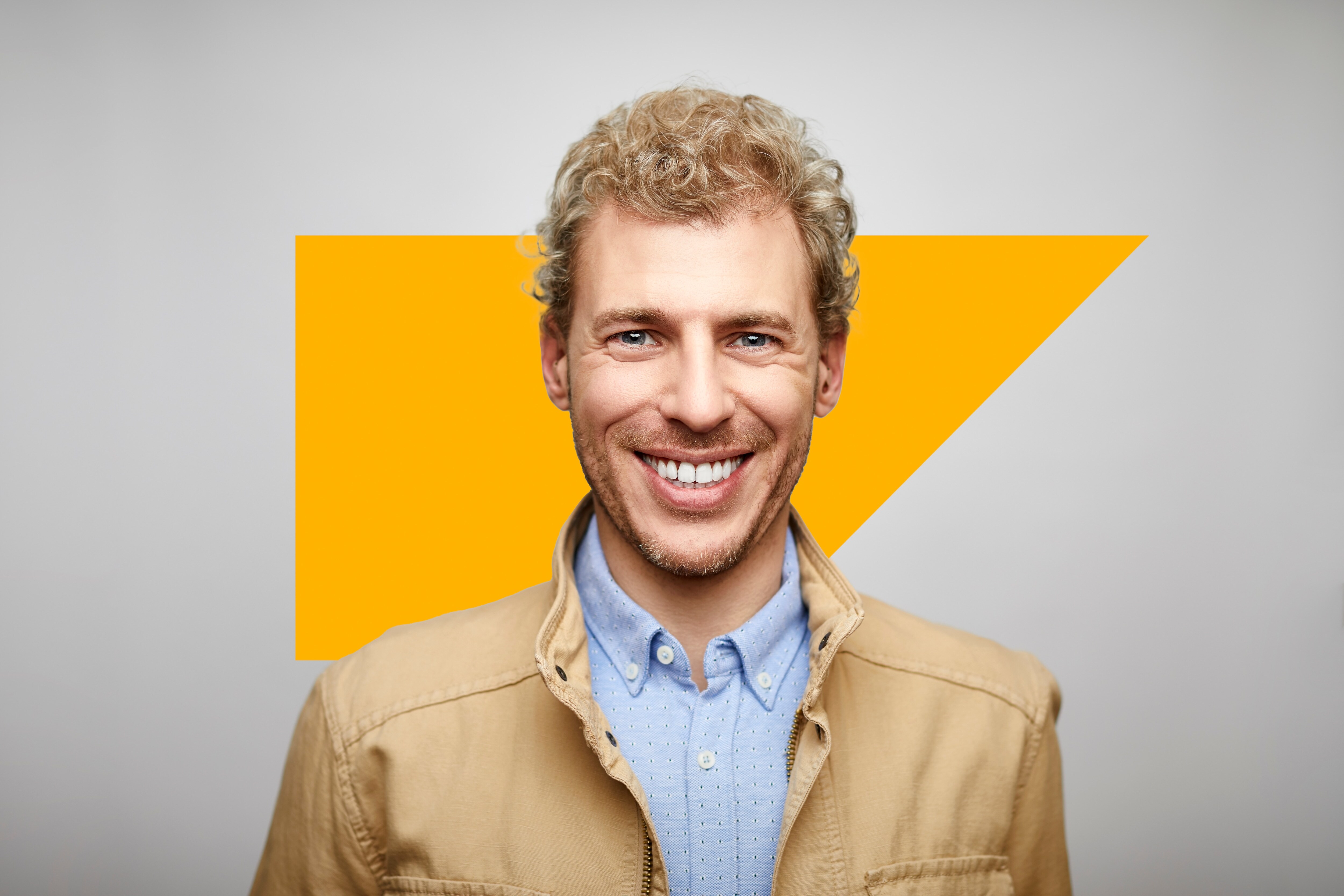 Man with blonde hair wearing a button up shirt smiling