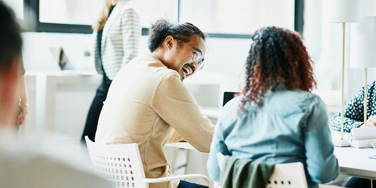 Two co-workers laughing and smiling while working together