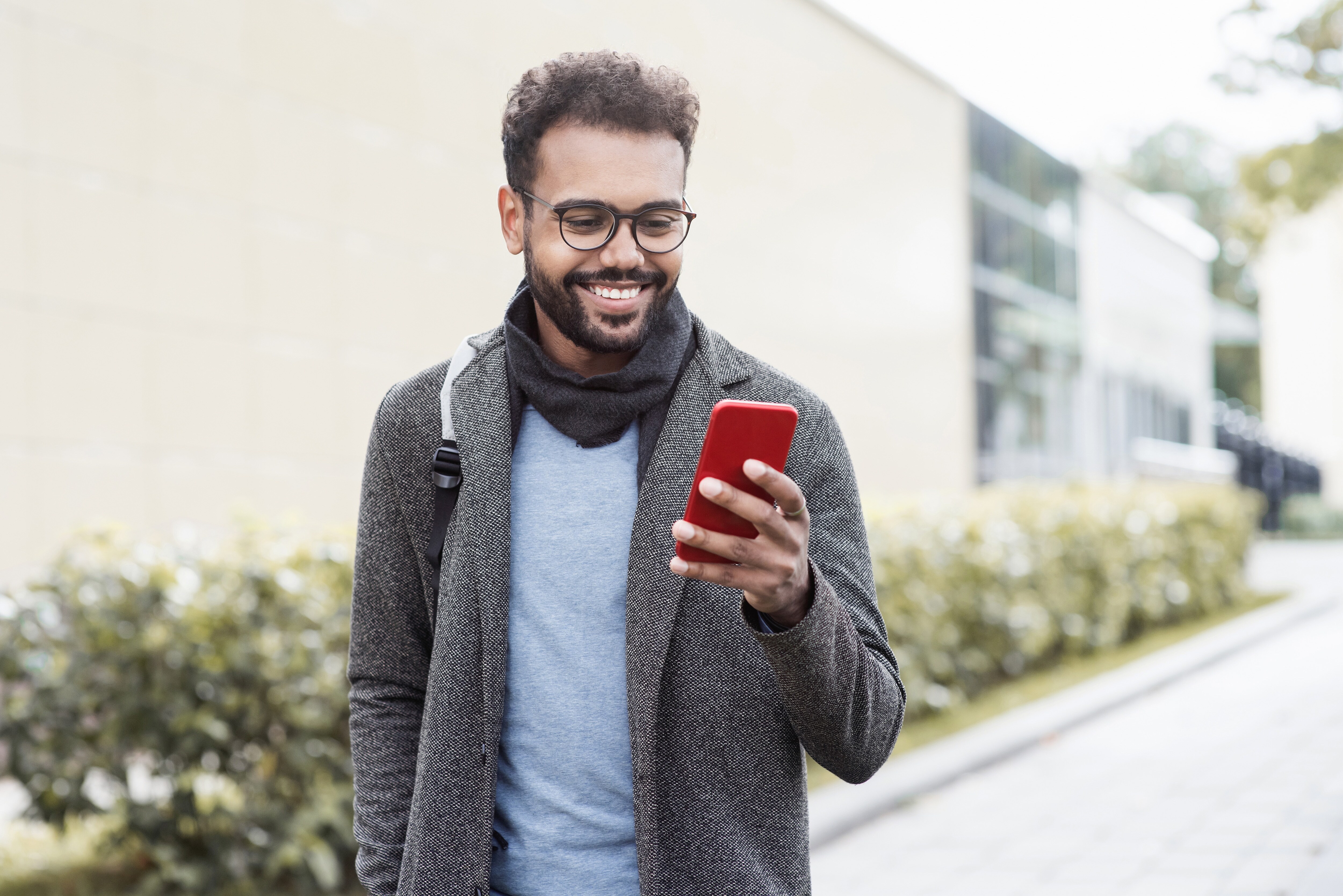 Man smiling with a backpack on looking at his phone