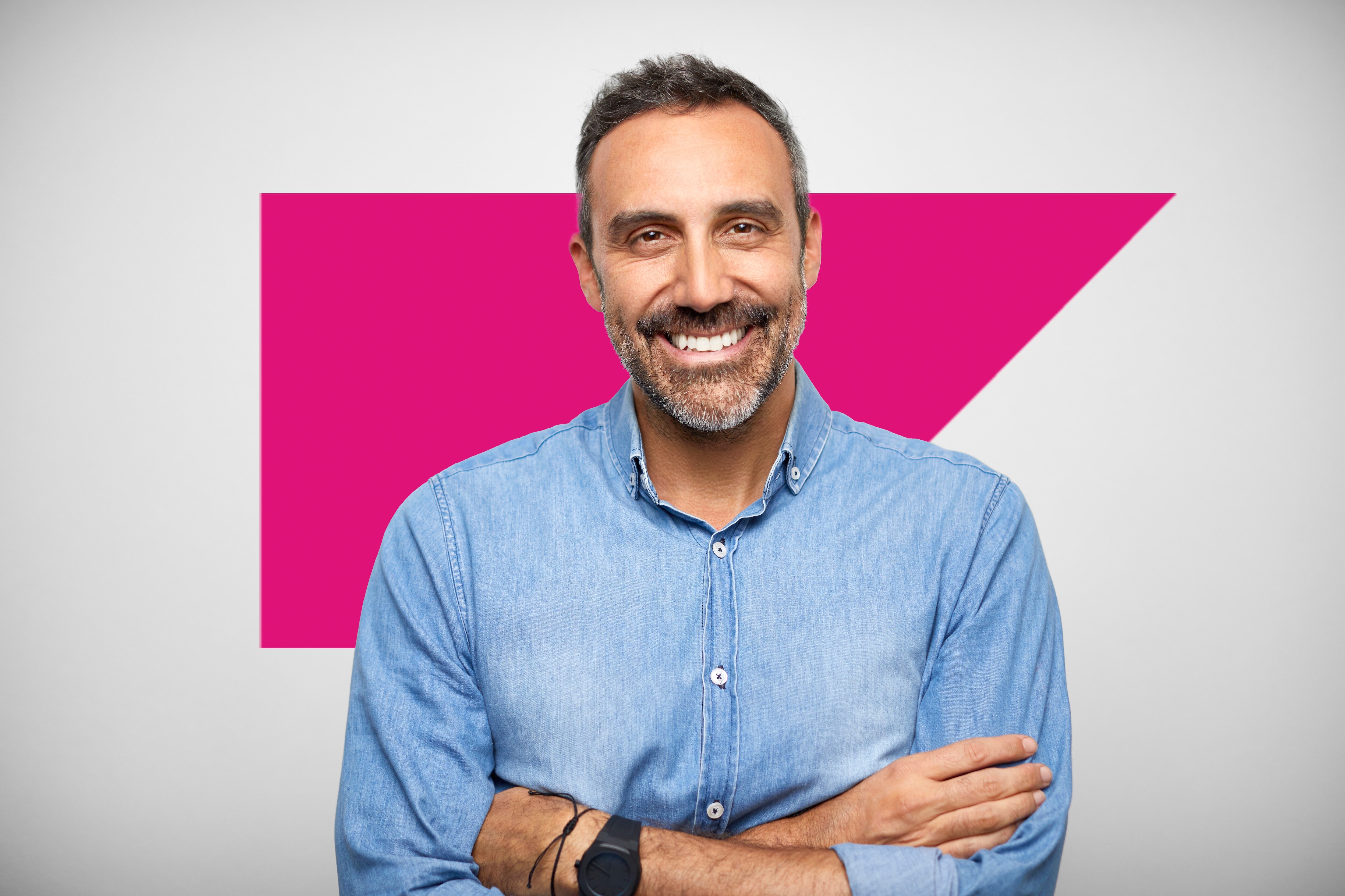 Man in a button down tshirt crossing his arms smiling