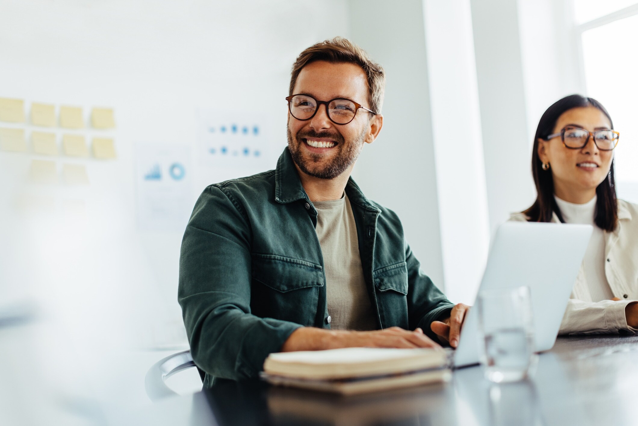 man smiling, table, whiteboard in background