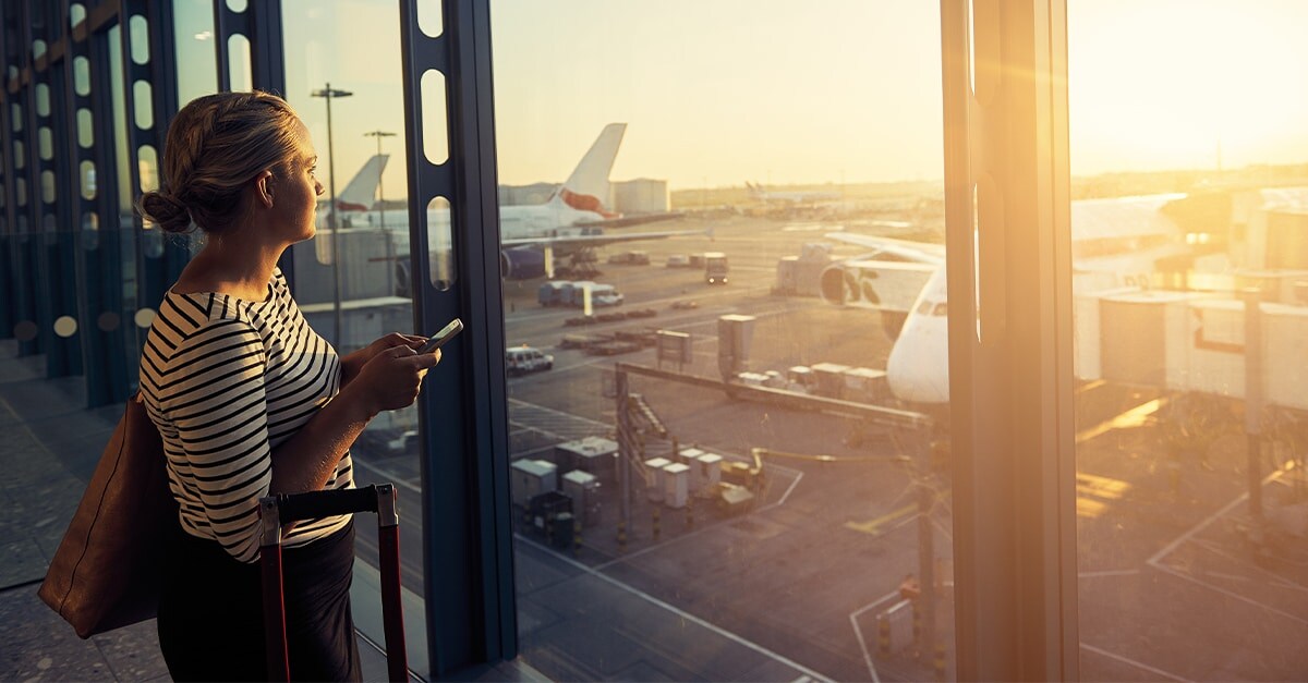 Woman looking out an airport window at an airplane