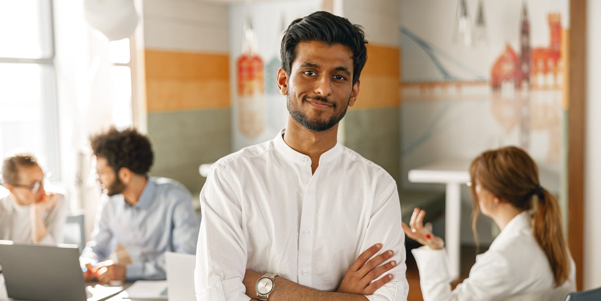 Young employee smiling at camera with arms crossed