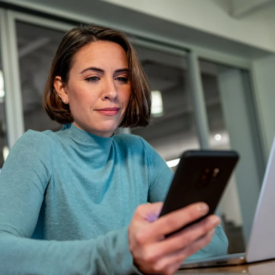 Woman in an office looks at her smartphone