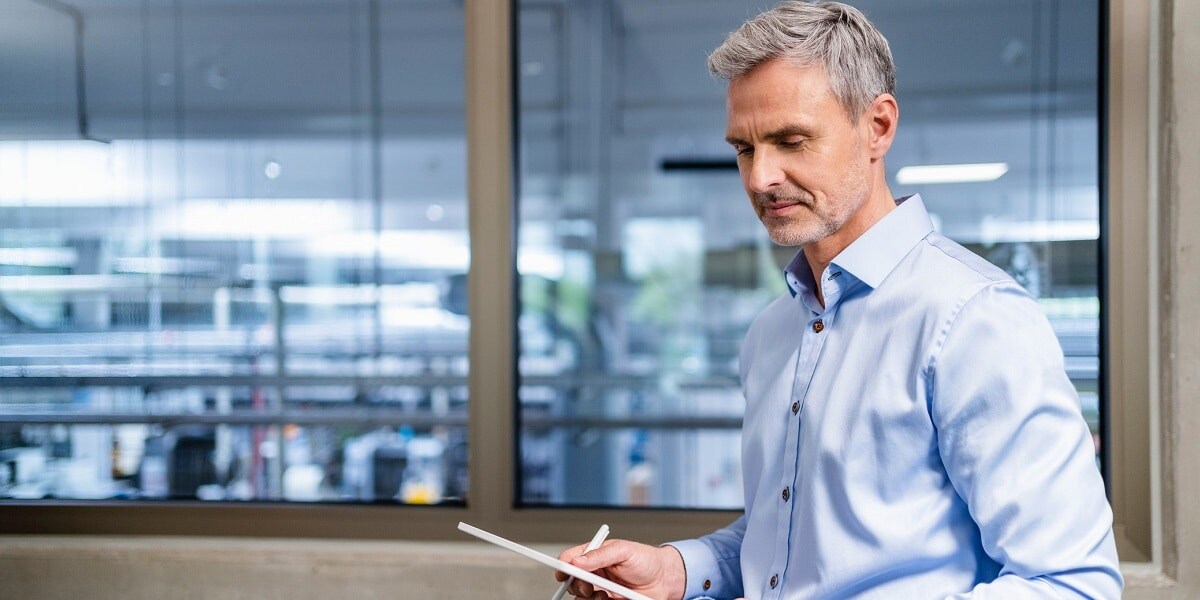 Man in a blue button-down shirt looking at a tablet computer